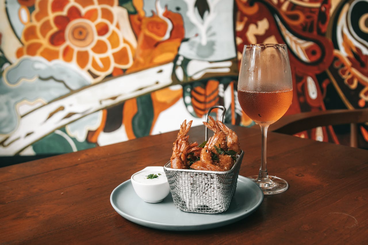 A stylish restaurant table setting with fried shrimp and a glass of wine.